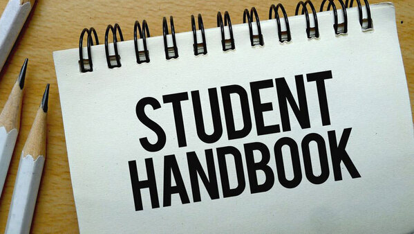 Notebook that has student handbook written on it with pencils
