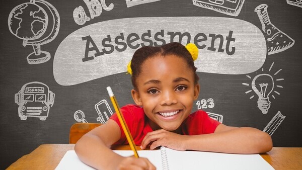 Girl smiling at camera with the word assessment behind her on a sudo-chalkboard