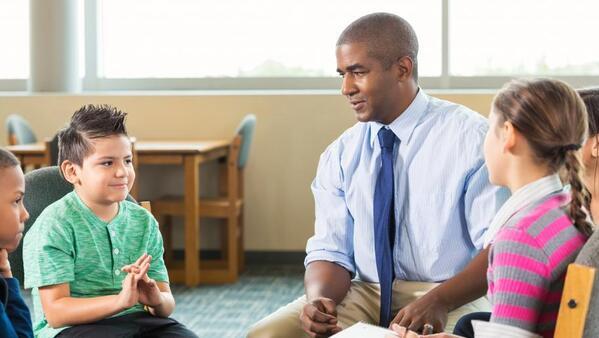 School counselor sitting talking with a group of students