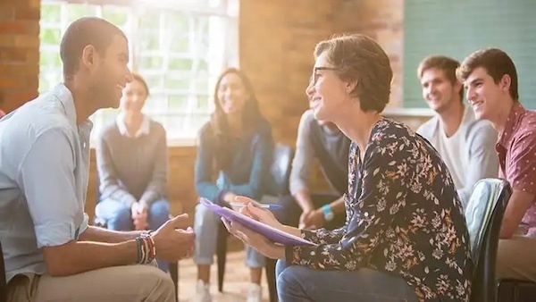 Woman speaking with a student. There are students blurred out in the background.