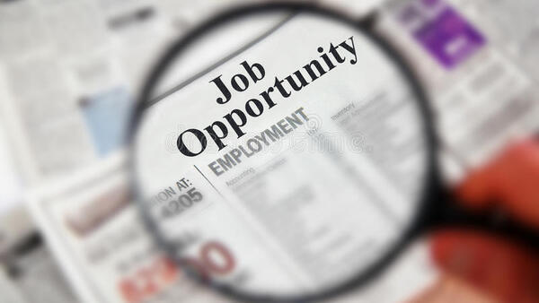 Magnifying glass looking at  old newspaper with Job Opportunities magnified.