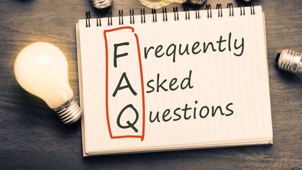 Frequently asked questions written on a pad of paper with FAQ circled. There are also light bulbs on the table