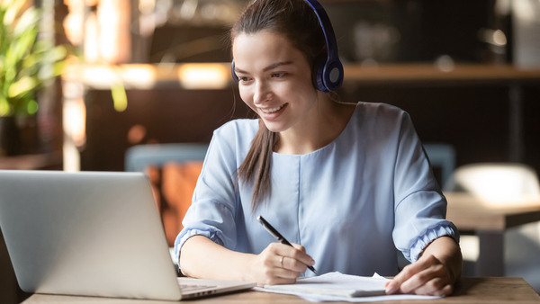 High school age student working on a laptop with headphones on.