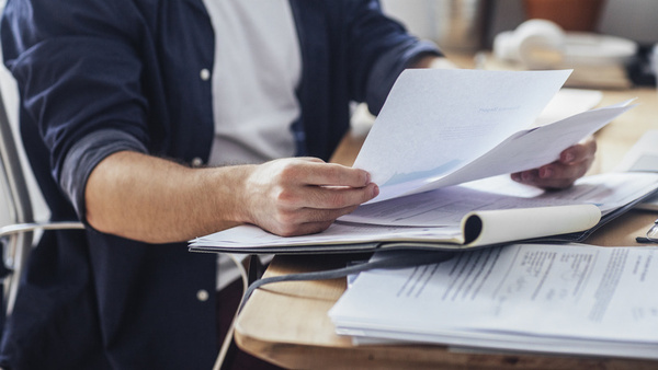 Man looking at papers with more papers on the table.