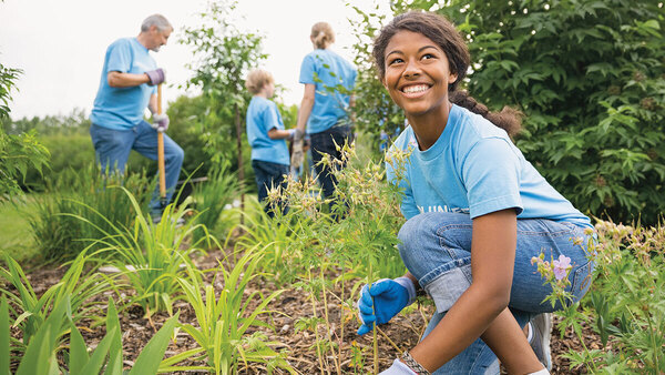 Female bending down picking weeds.