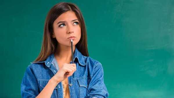 Female student holding pencil near her mouth  deep in thought