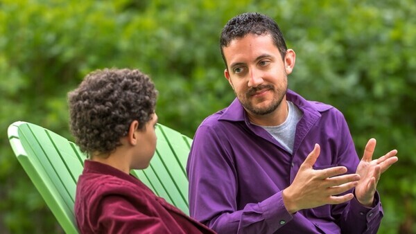 Man and boy sitting in chairs appearing to talk