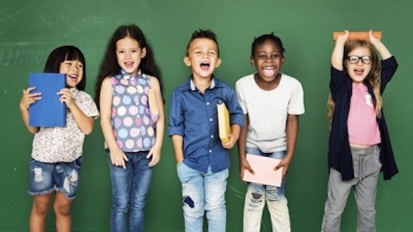 Group of elementary age students facing the camera acting silly.