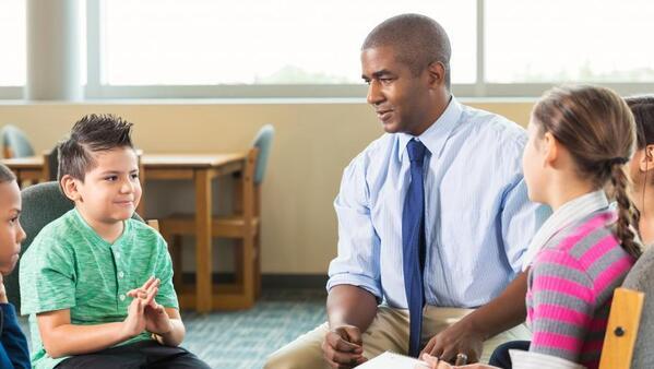 School counselor sitting talking with a group of students.