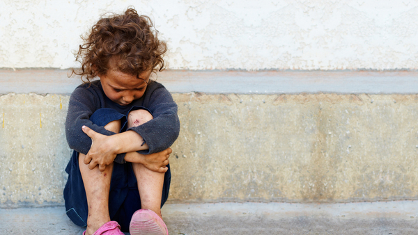 Child appearing to be homeless sitting on curb