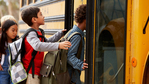 Students climbing about a school bus.