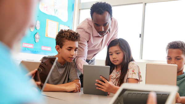 Teacher assisting elementary students on computers