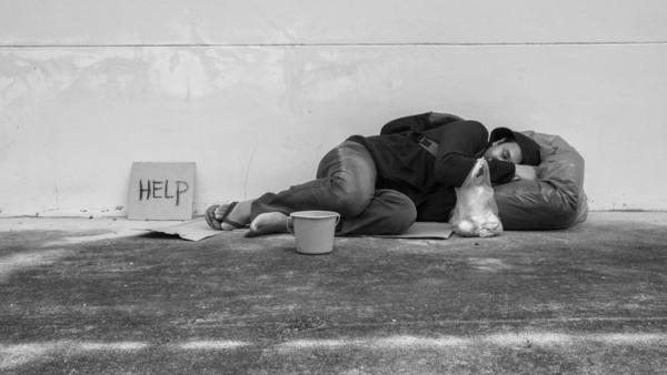 Homeless person sleeping on ground with help sign