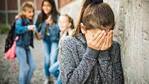 Girl being bullied with girls behind blurred out pointing and laughing