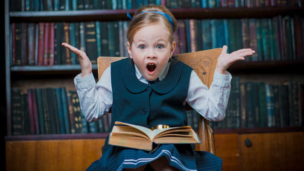 girl with surprised look sitting with open book on her lap